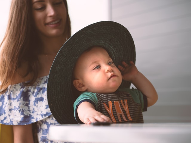 帽子を被る赤ちゃんと見守る母親