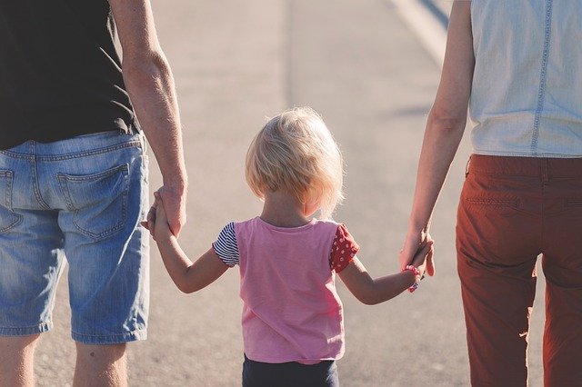 女の子と両親が手をつなぎ歩いている