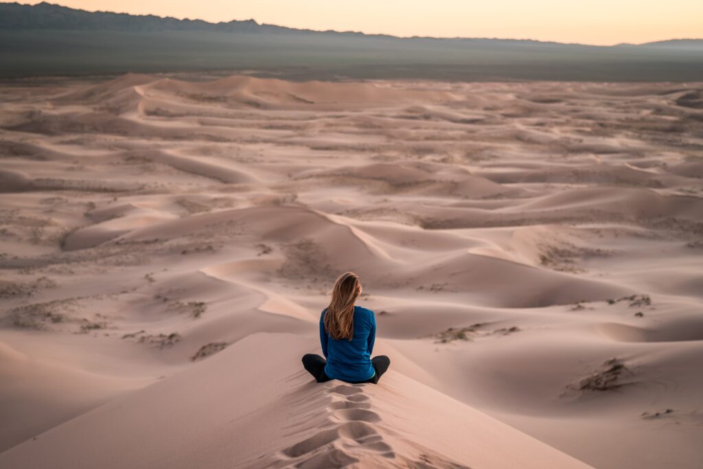 寂しそうに砂漠に座ってる女性